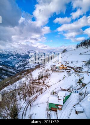 Luftaufnahme einer kurvenreichen Straße durch verschneite Landschaft in den Bergen von Asturien in Spanien. Winterzeit. Stockfoto