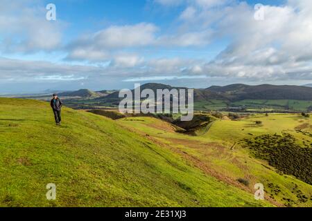 Solo-Hikerin auf dem Long Mynd, Shropshire, England, mit Caer Caradoc, dem Lawley, mit dem Wrekin in der Ferne. Stockfoto