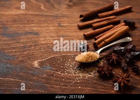 Verschiedene natürliche Zimt, Rohrbrauner Zucker, gemahlener Kaffee, Anis Sterne Backzutaten auf einem rustikalen braunen Hintergrund. Stockfoto