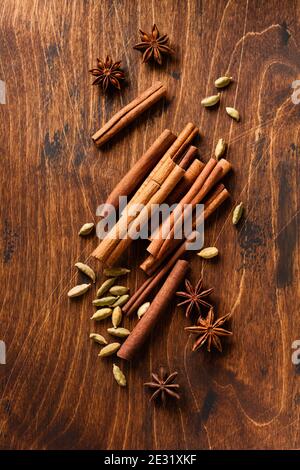 Verschiedene natürliche Zimt, Kardamome und Anis Sterne Backzutaten auf einem rustikalen braunen Hintergrund. Stockfoto