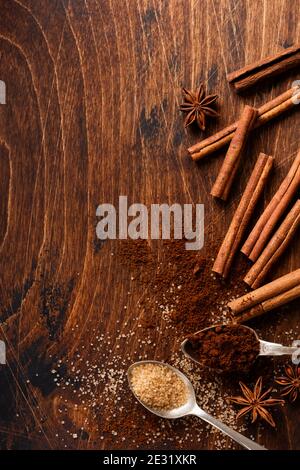 Verschiedene natürliche Zimt, Rohrbrauner Zucker, gemahlener Kaffee, Anis Sterne Backzutaten auf einem rustikalen braunen Hintergrund. Stockfoto