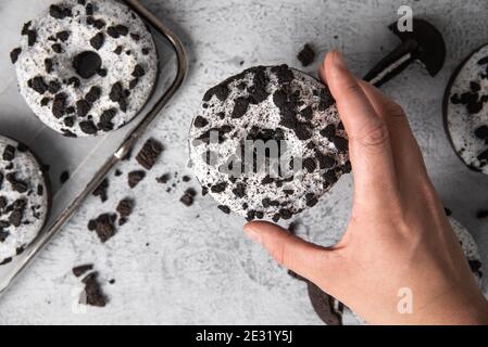 Draufsicht auf einige leckere Donuts mit Keksen bedeckt In einer menschlichen Hand Stockfoto