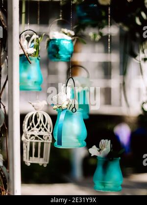 Hochzeitsdekor mit hängenden blauen kleinen Glasvasen und weißen Blumen Stockfoto