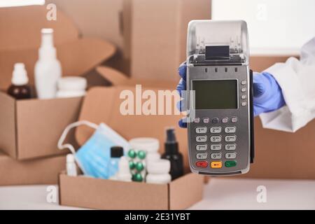 Nahaufnahme mit der Hand eines Apothekers, der ein POS-Terminal hält Stockfoto