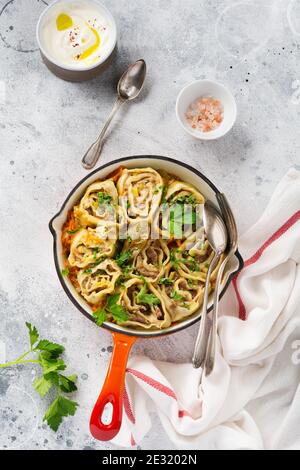 Fleischteig rollt mit Fleisch oder "faulen Knödeln" in einer gusseisernen Pfanne auf einem alten rustikalen grauen Hintergrund. Draufsicht. Stockfoto