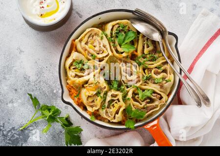 Fleischteig rollt mit Fleisch oder "faulen Knödeln" in einer gusseisernen Pfanne auf einem alten rustikalen grauen Hintergrund. Draufsicht. Stockfoto