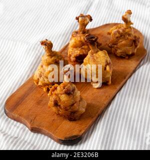 Hausgemachtes würziges Huhn Lollipop auf einem rustikalen Holzbrett, Seitenansicht. Stockfoto