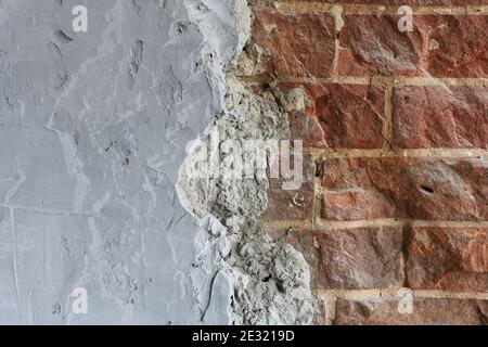 Graue Betonoberfläche mit rotem Ziegelmauerwerk. Zusammengesetzter abstrakter Hintergrund mit zu kopierenden Leerzeichen. Stockfoto