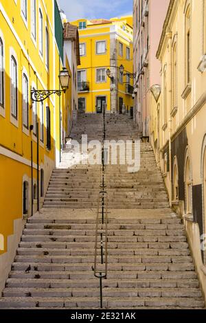 Typische steile Straße mit langen Treppen und bunten Mauern der Stadt Lissabon, Portugal. Stockfoto