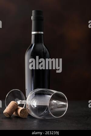 Flasche Wein und leeres klassisches Weinglas mit Korken auf dunklem Hintergrund. Stockfoto