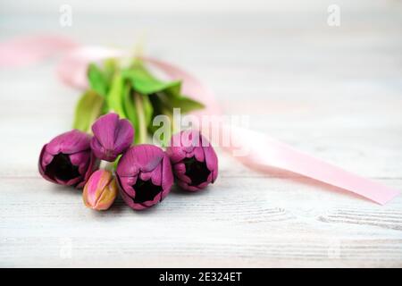 Blumen, lila Tulpen liegen auf einem hellen Holzhintergrund. Seitenansicht. Stockfoto
