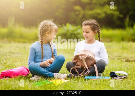 Zwei hübsche Schülerinnen sitzen mit Büchern im Park. Schülerinnen oder Schülern wird Unterricht in der Natur beigebracht. Stockfoto