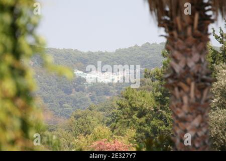 Fantastische Aufnahme einer winzigen Stadt, die von den Bergen umgeben ist Durch die Bäume Stockfoto
