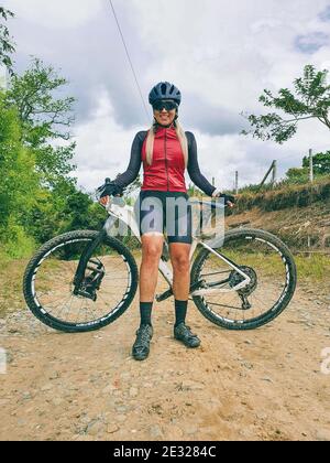 Vertikale Aufnahme einer schönen Radfahrerin mit ihrem Berg Fahrrad in den Bergen Stockfoto