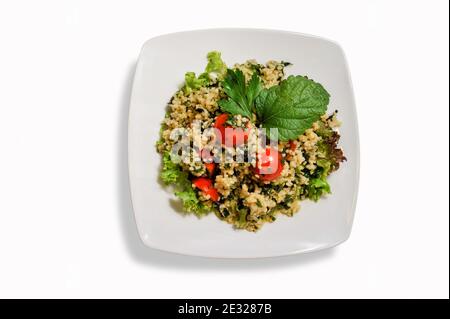 Tabbouleh von Couscous - Couscous Salat und Gemüse in einem weißen Teller isoliert auf weißem Hintergrund Draufsicht. Speicherplatz kopieren. Stockfoto