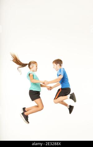 Cute boy in Sportswear unter die Hände von charmanten Mädchen beim Springen in die Luft. Isoliert auf weißem Hintergrund Stockfoto