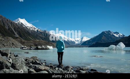 Touristen stehen am Ufer des Tasman Glacier Terminal Lake Blick auf schneebedeckte Berge und Eisberge Stockfoto