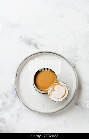 Kondensierte oder verdampfte Milch in offener Dose auf hellem Betontisch. Draufsicht. Stockfoto