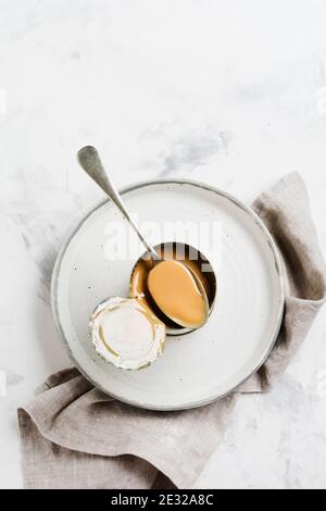 Kondensierte oder verdampfte Milch in offener Dose auf hellem Betontisch. Draufsicht. Stockfoto