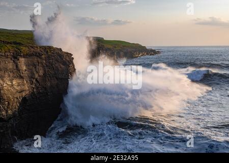 Große Wellen krachen bei Sonnenuntergang gegen die Klippen in Doolin, Co. Clare Ireland, Wild Atlantic Way Stockfoto