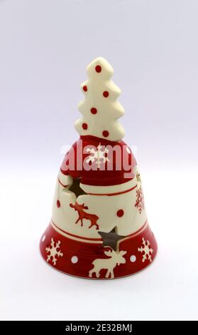 Foto einer keramischen roten und cremefarbenen Glocke Weihnachten Thema mit Rentieren und Eiskristallen und einem Weihnachtsbaum Griff auf weißem Hintergrund Stockfoto