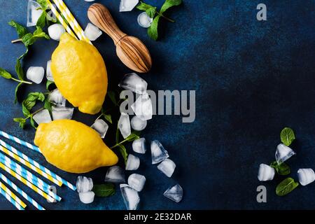 Zwei frische Zitronen in dunkelblauem Teller auf türkisfarbenem Betongrund. Hintergrund für das Essen. Draufsicht. Stockfoto