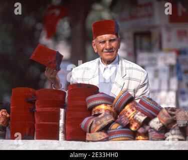 Mann, der türkische Fez-Hüte verkauft, Taksim-Platz, Taksim-Bezirk, Istanbul, Republik Türkei Stockfoto