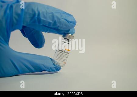 Eine Handschelle mit Sinovacs Coronavac-Impfstoff (SARS-Cov-2) in der Mitte eines weißen Hintergrunds. Selektiver Fokus. Stockfoto