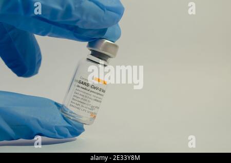 Eine Handschelle mit Sinovacs Coronavac-Impfstoff (SARS-Cov-2) in der Mitte eines weißen Hintergrunds. Selektiver Fokus. Stockfoto