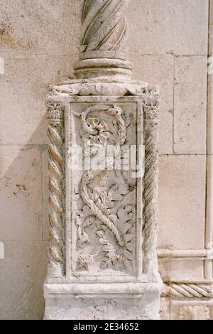 Steinmauer mit einem blumenförmigen Flachrelief an einer Säule. Stockfoto