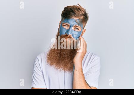 Junger irischer Rotschopf Mann trägt Gesichtsmaske denken müde aussehen und gelangweilt mit Depressionen Probleme mit gekreuzten Armen. Stockfoto