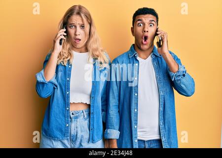 Junge interracial Paar mit Gespräch auf dem Smartphone Angst und erstaunt mit offenem Mund für Überraschung, Unglauben Gesicht Stockfoto