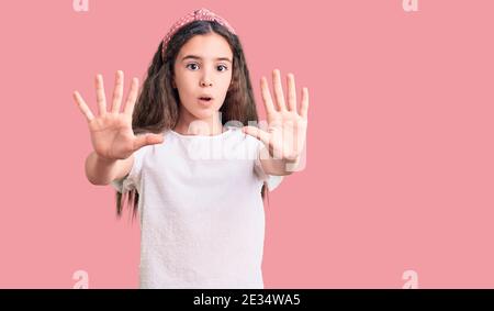 Cute hispanischen Kind Mädchen tragen beiläufige weiße T-Shirt tun Stop-Geste mit Händen Handflächen, wütend und Frustration Ausdruck Stockfoto