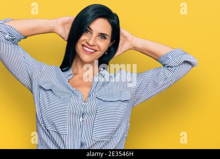 Junge kaukasische Frau trägt lässige Kleidung entspannend und Stretching, Arme und Hände hinter Kopf und Hals lächelnd glücklich Stockfoto