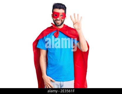 Junger schöner Mann mit Bart trägt Superhelden Kostüm zeigt und zeigt mit den Fingern Nummer vier, während lächelnd zuversichtlich und glücklich. Stockfoto