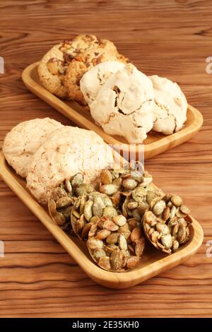 Haferflockenplätzchen mit Walnüssen und Rosinen, mit Zucker beschichtete Kürbiskernplätzchen, Baiser-Plätzchen mit Haselnüssen, Mandelplätzchen in einem Bambusteller auf einem Stockfoto