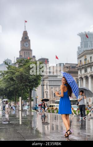 China Reise Tourist Frau zu Fuß in Shanghai Stadt unter dem Regen mit Regenschirm. Asiatische Frau zu Fuß durch Bund Fluss glücklich Spaziergang auf Asien China reisen Stockfoto