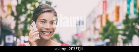 Walking junge asiatische Frau in der Stadt Straße Anruf auf Handy sprechen dabei einen Anruf Banner Panorama. Lächelnd gemischtes Rennmädchen Stockfoto