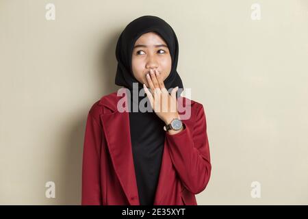 Junge asiatische Frau trägt Hijab schockiert Abdeckung Mund mit Händen für Fehler. Geheimes Konzept. Stockfoto