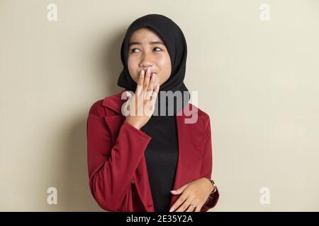 Junge asiatische Frau trägt Hijab schockiert Abdeckung Mund mit Händen für Fehler. Geheimes Konzept. Stockfoto