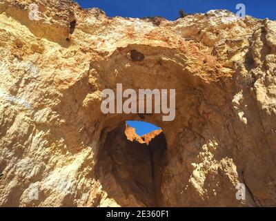 Praia da Vau mit einer Höhle mit einem Loch in den blauen Himmel in Portimao, algarve Küste, Portugal Stockfoto