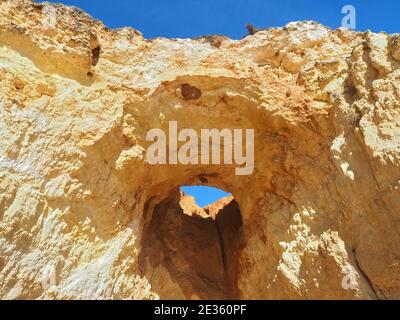 Praia da Vau mit einer Höhle mit einem Loch in den blauen Himmel in Portimao, algarve Küste, Portugal Stockfoto