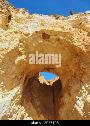 Praia da Vau mit einer Höhle mit einem Loch in den blauen Himmel in Portimao, algarve Küste, Portugal Stockfoto