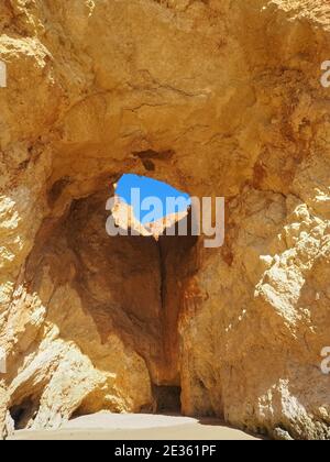 Praia da Vau mit einer Höhle mit einem Loch in den blauen Himmel in Portimao, algarve Küste, Portugal Stockfoto