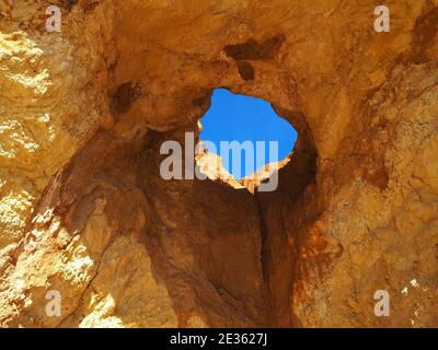 Praia da Vau mit einer Höhle mit einem Loch in den blauen Himmel in Portimao, algarve Küste, Portugal Stockfoto