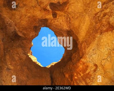 Praia da Vau mit einer Höhle mit einem Loch in den blauen Himmel in Portimao, algarve Küste, Portugal Stockfoto