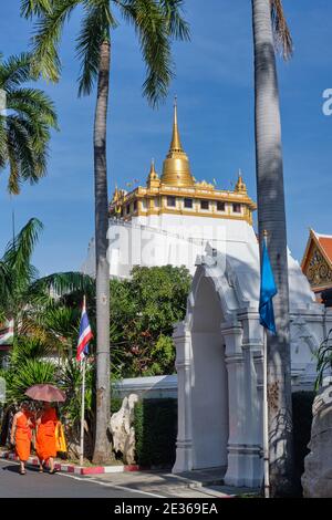 Buddhistische Mönche im weitläufigen Gelände des Wat Saket, Bangkok, Thailand, mit dem ikonischen Goldenen Berg (Phukhao Thong) im Hintergrund Stockfoto