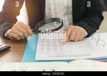 Business Frauen mit Lupe Bilanz jährlich zu überprüfen. Konzept der internen Revision, Steuerprüfung, Analyse der Rendite auf Investitionen. Stockfoto