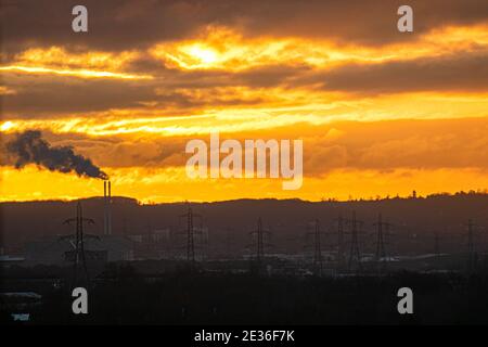 WIMBLEDON LONDON, GROSSBRITANNIEN 17. JANUAR 2021. Rauchwolken aus einem Kamin und Sendetürmen eines Kraftwerks, die an einem kalten Morgen gegen den farbenfrohen Sonnenaufgang über Wimbledon schillerten. Kredit: amer ghazzal/Alamy Live Nachrichten Stockfoto