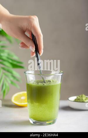 Frau, die Wasser mit grünem Superfood Pulver mischt Stockfoto